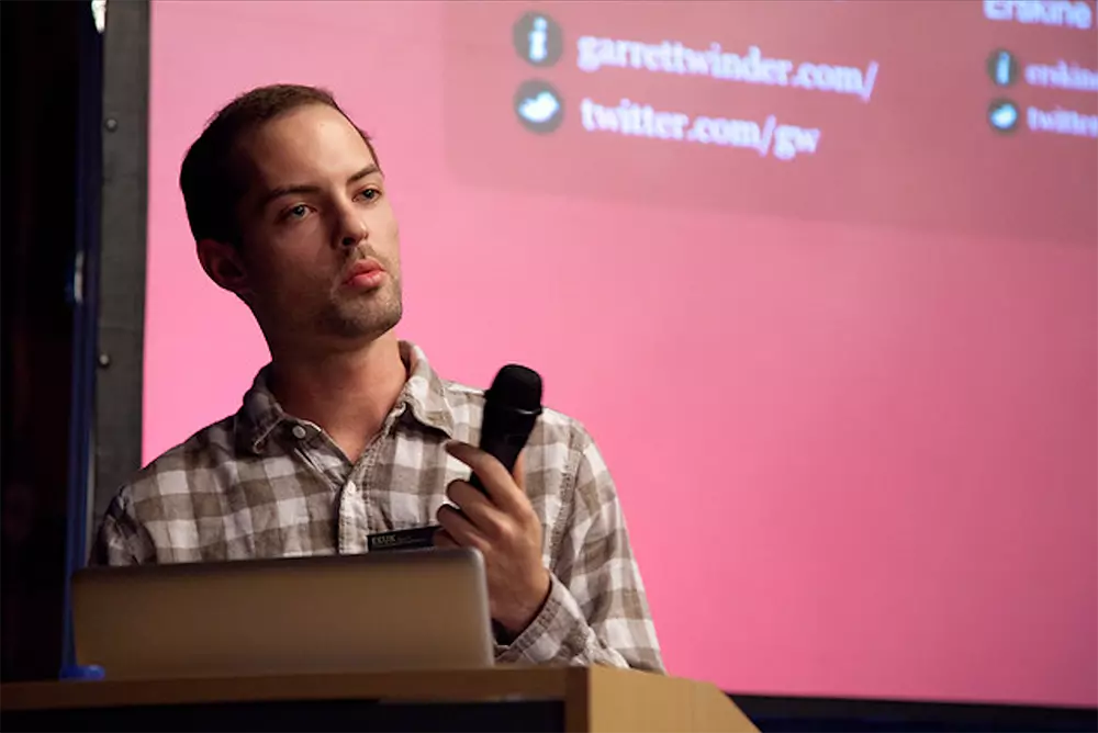 A group of people sitting around a table with food and drinks at a venue with an 'All City Ping Pong Invitational' sign in the background.